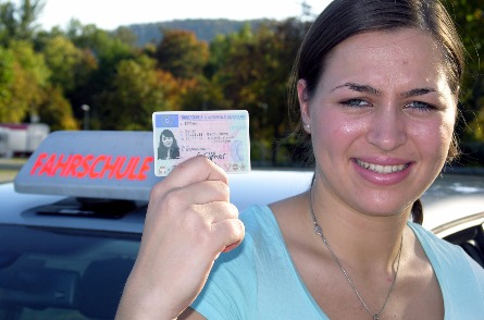 Schülerin zeigt nach bestandener Prüfung stolz ihren Führerschein.